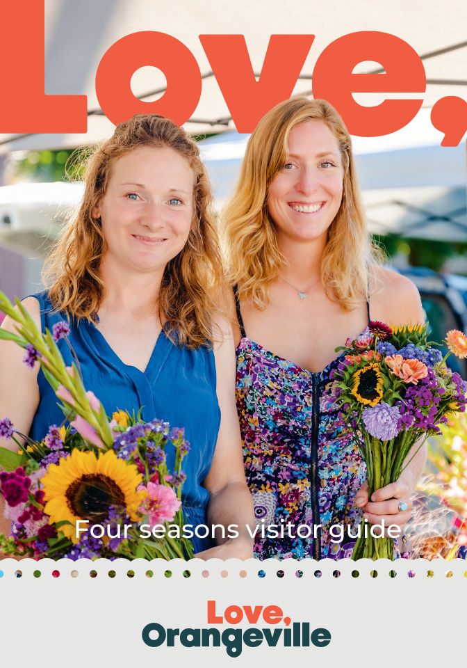 Cover of Orangeville Visitor Guide. There are two women smiling and holding flowers.